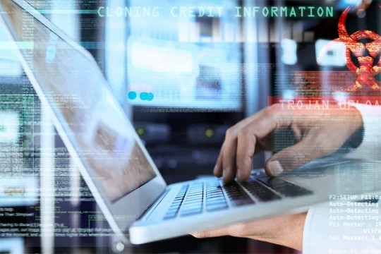 male hands hold a laptop and type. In the background, computer code appears.