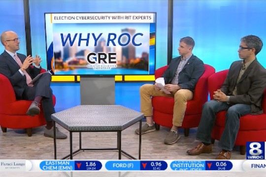 three men sit in chairs on a news station set.