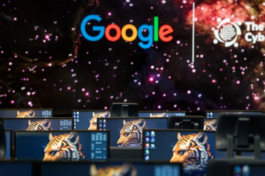 A computer lab with the Google logo displayed on a background and tiger heads displayed on computer screens
