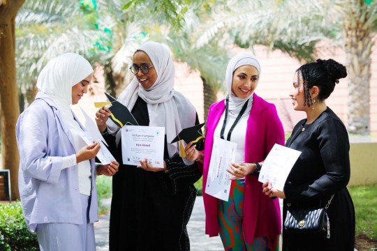 Four women stand at a graduation.
