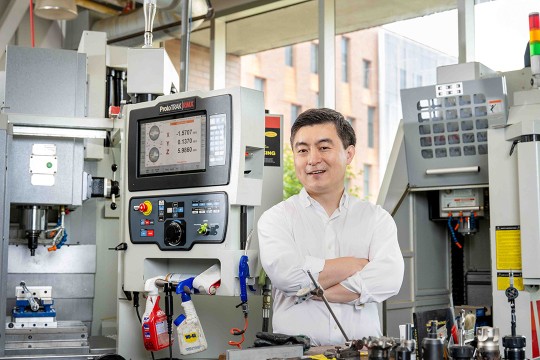 a man in a white shirt stands in a lab.
