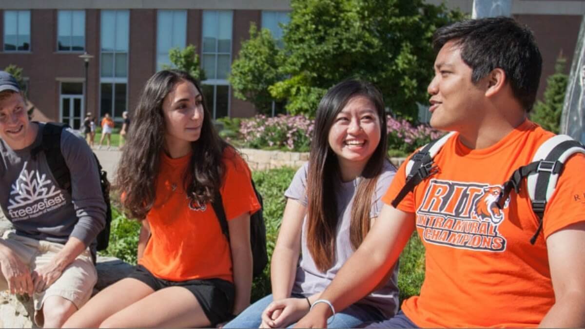 Four R I T students sitting in a quad on campus.