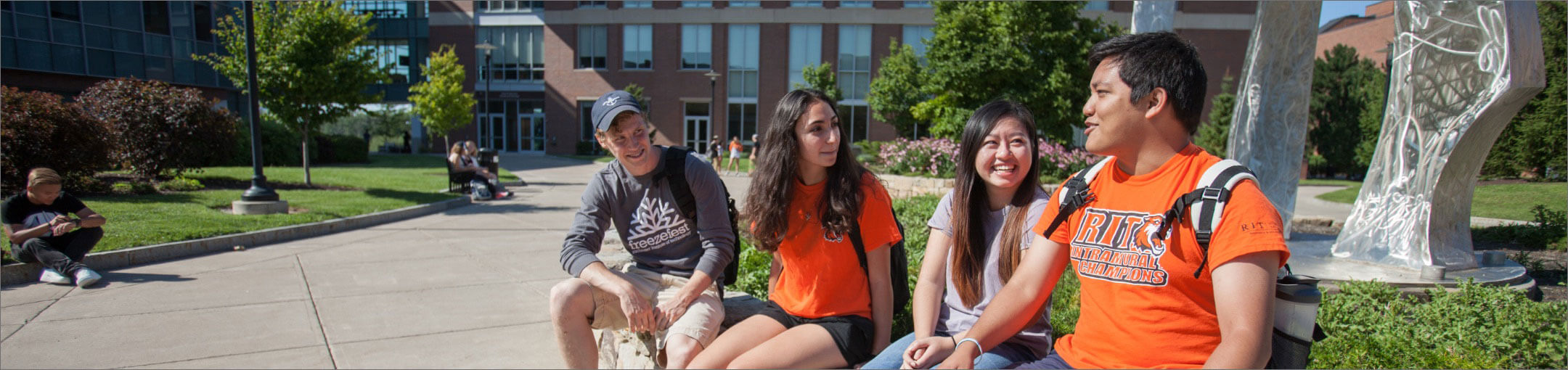 Four R I T students sitting in a quad on campus.