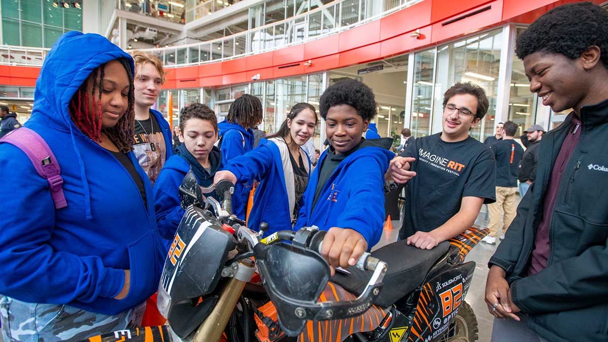 A group of students gather around and examine a motorbike inside a bright innovation center.