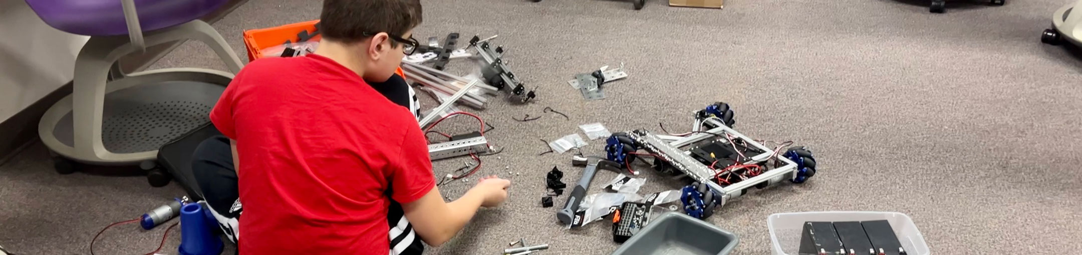 a younger student working on a small robotic vehicle