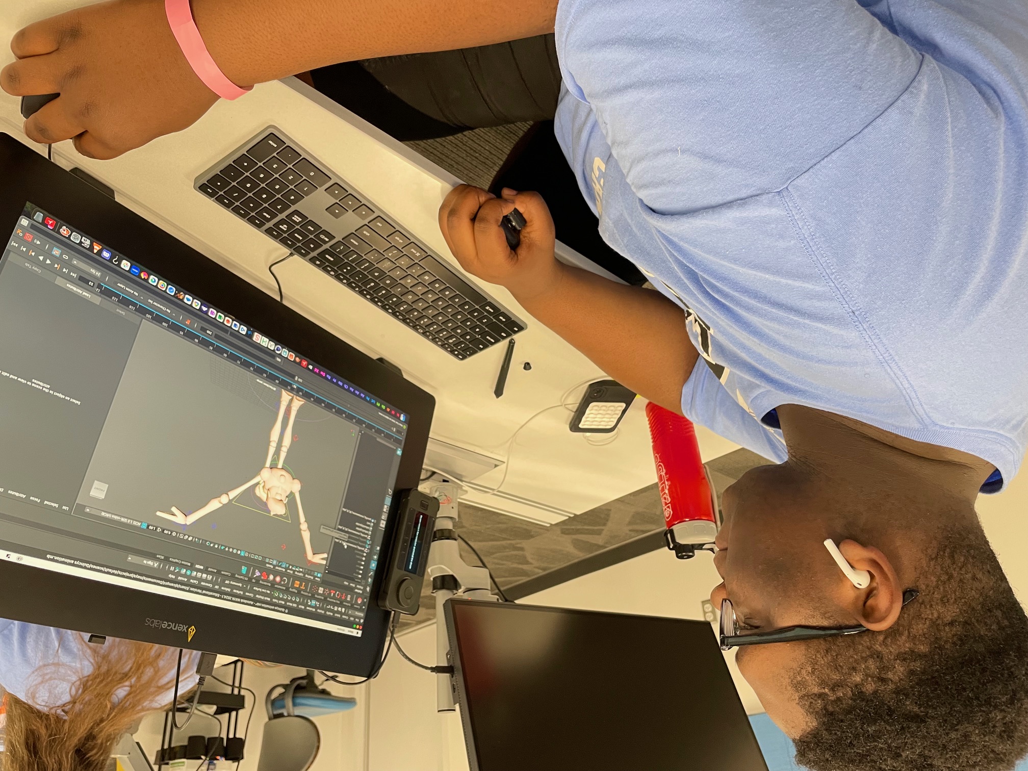 Youth in blue t-shirt working on animation project on a computer.