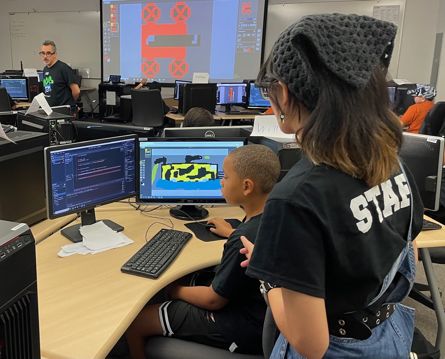 Staff assisting youth on computer at Jr. Game Development Program for Camp Tiger