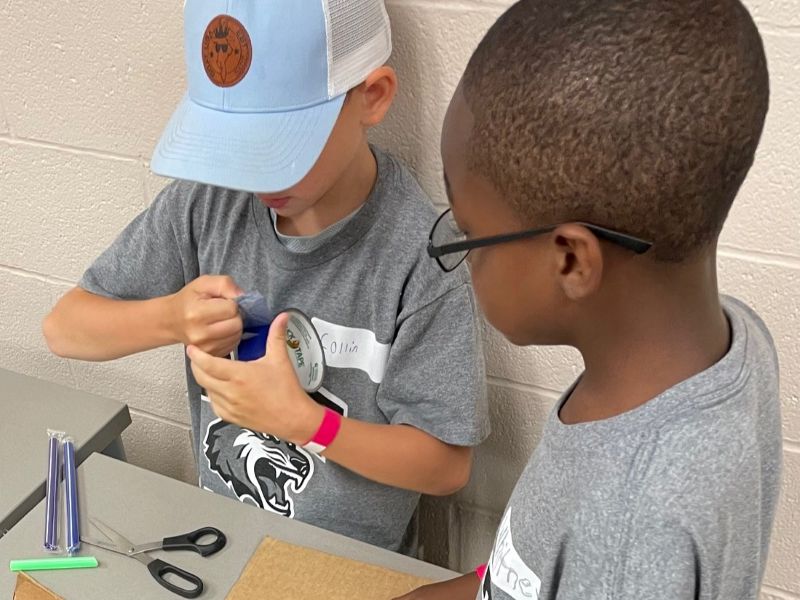 Two boys in grey t-shirts working on a project together.