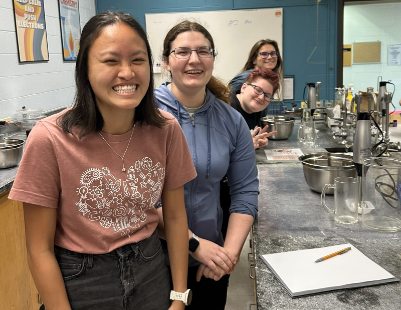 Four students in a biochemistry lab, standing next to a work table.