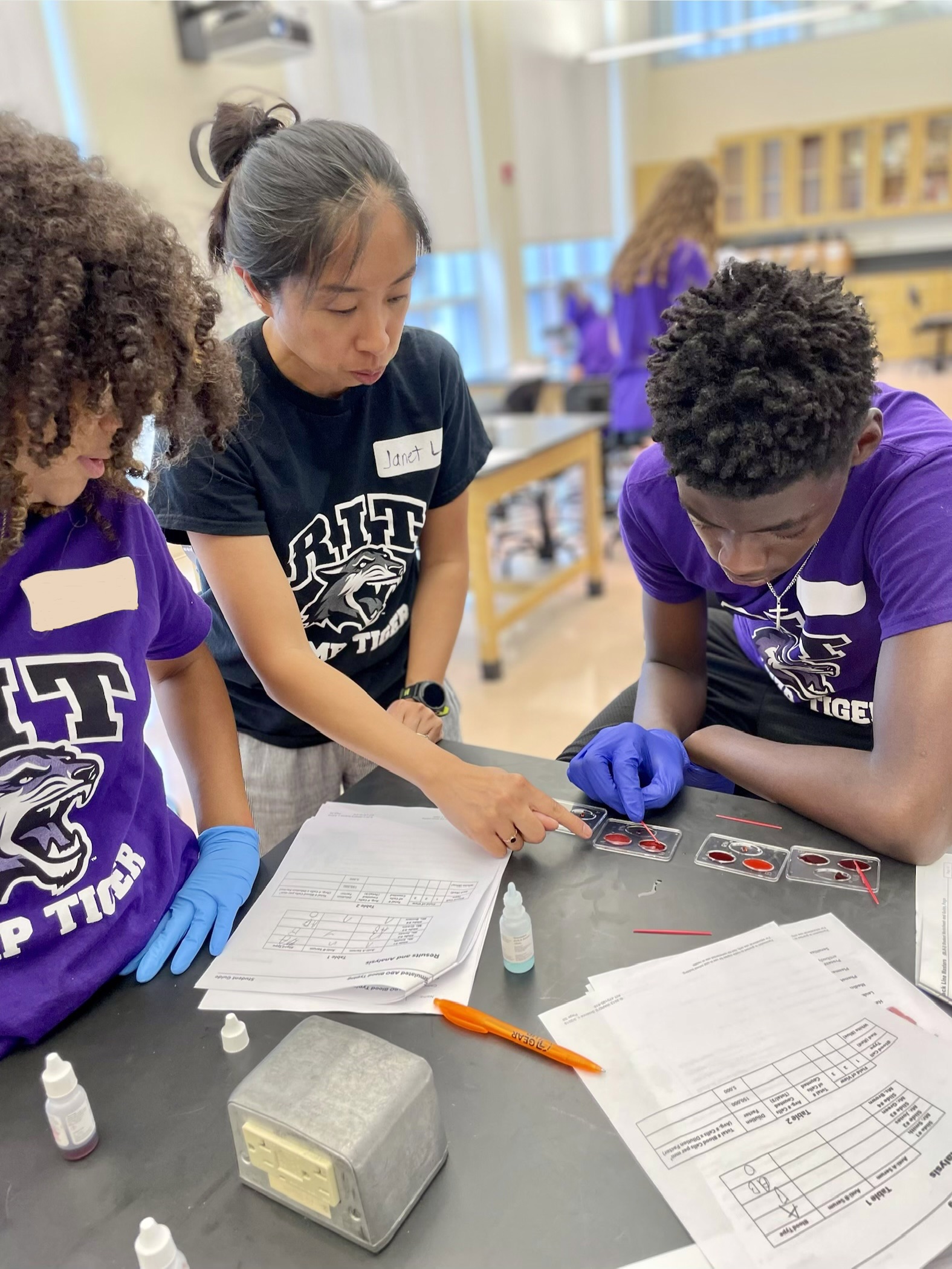 Professor working with two students on synthetic blood sample testing.