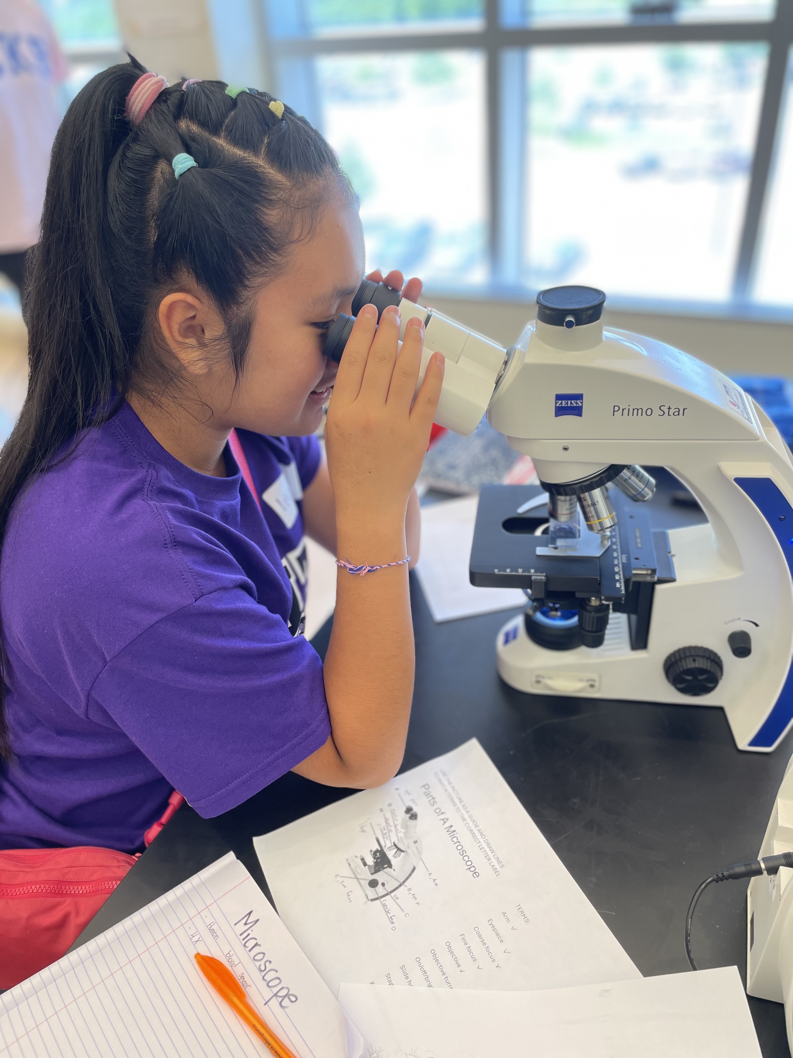 Youth looking into a microscope, working on a project in a lab.