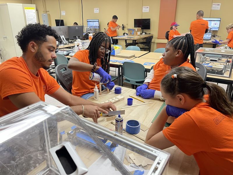 Students working with staff on a manufacturing engineering project in a lab.
