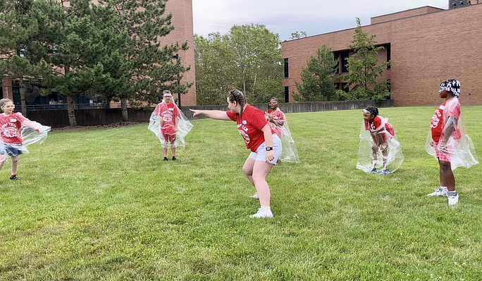 Group of youth playing a game of tag outdoors with a counselor.