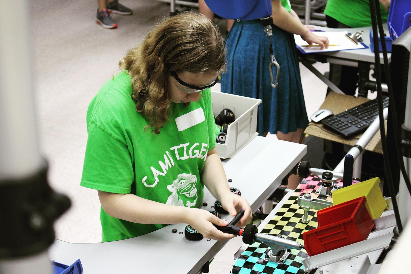 Camp Tiger camper working on an assembly line putting a skateboard together with other campers.