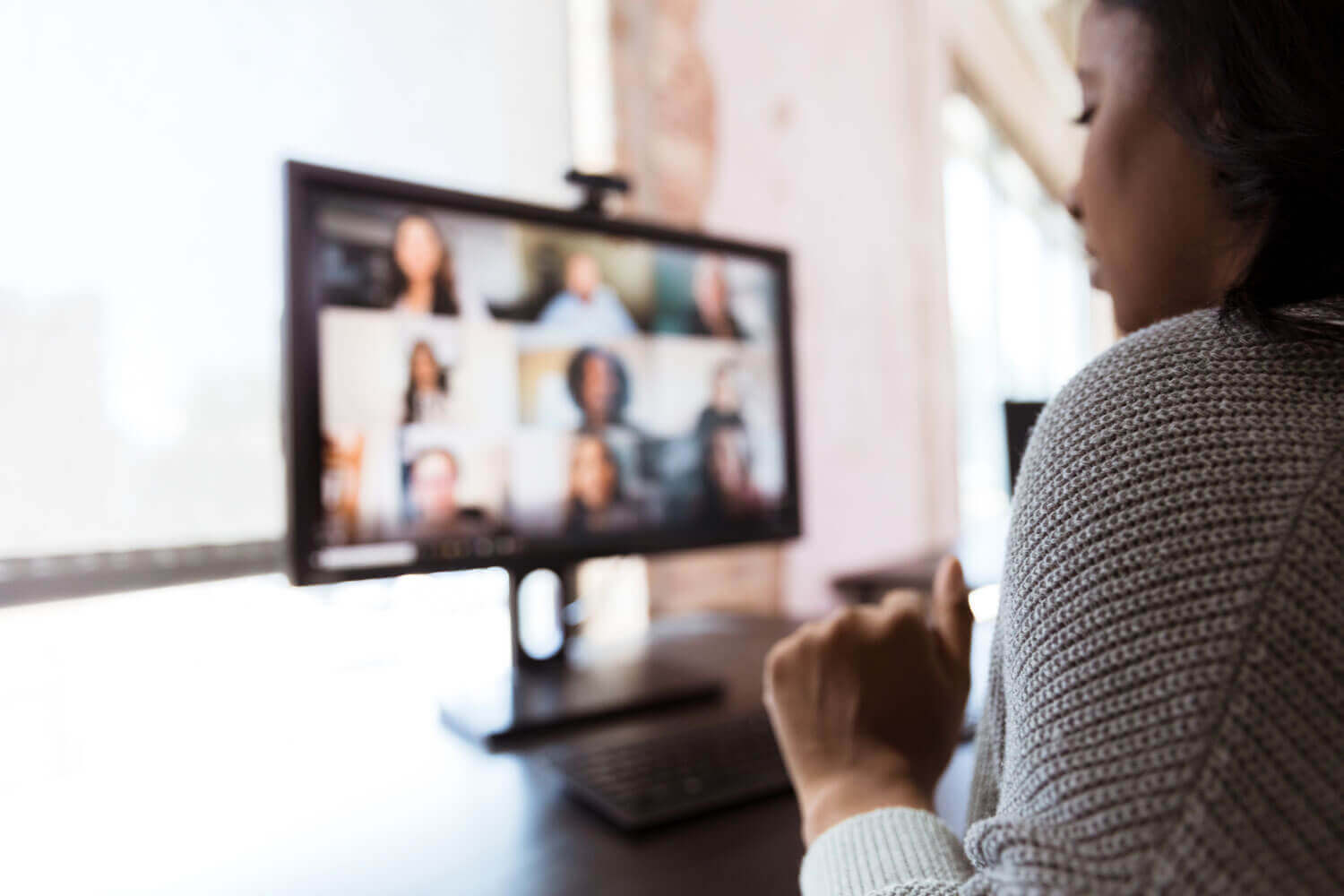 A person looking at a screen showing a video call between several people.