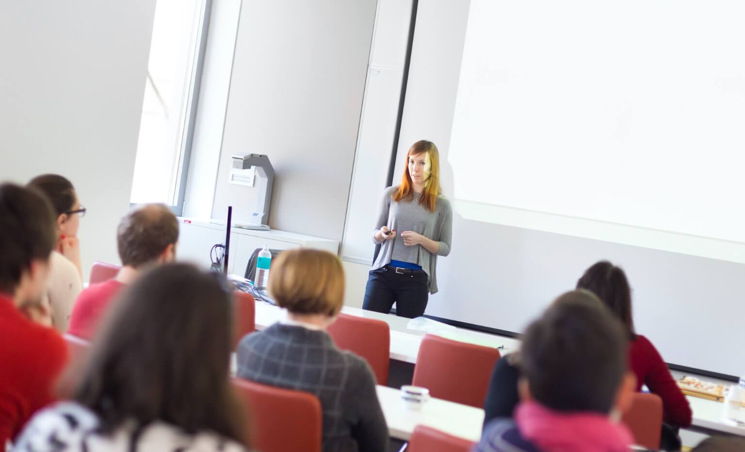 A person speaking in front of a room full of people.