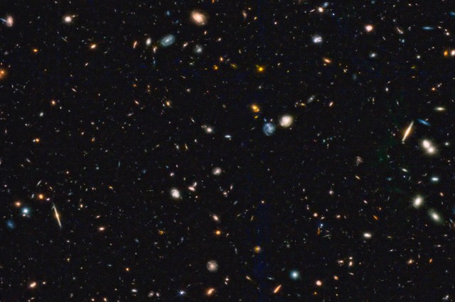 image from a space telescope showing specks and blobs of differing sizes and colors.