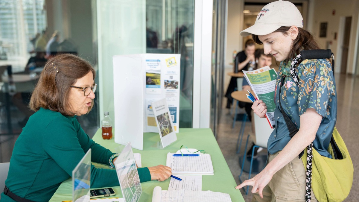 A student at a table talking to a representative looking at paper 