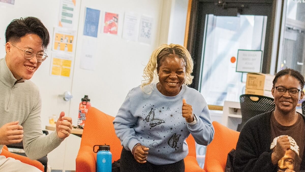 3 students smiling and dancing in a classroom during a momentum program