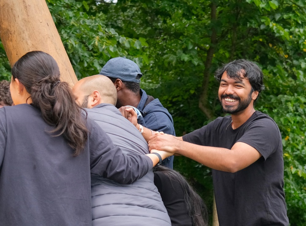 Student smiling while participating with others in a leadership bonding activity in the woods
