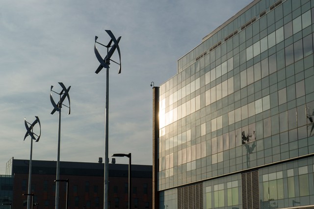 Three wind turbines in front of glass building.