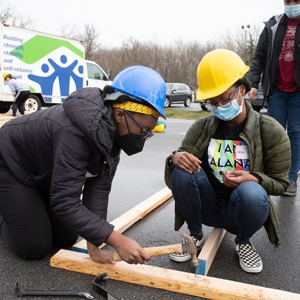two students building a wall frame for a house.