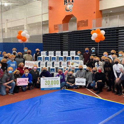 group of people posing for a photo around a pyramid of boxes.