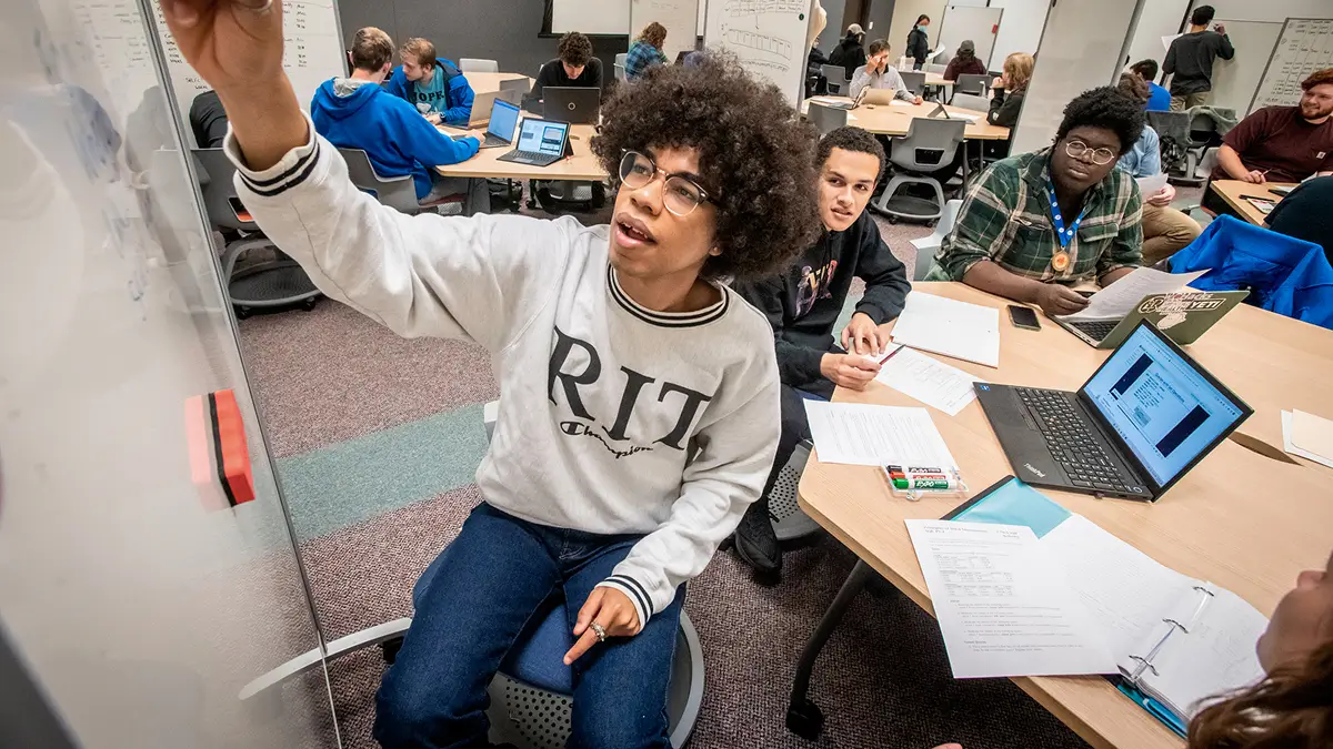 A learning assistant in a room, helping a group of students.