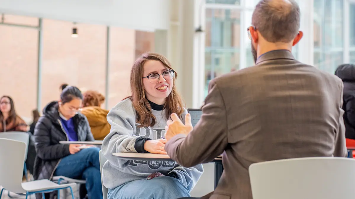 A student sitting at a table with a professor.