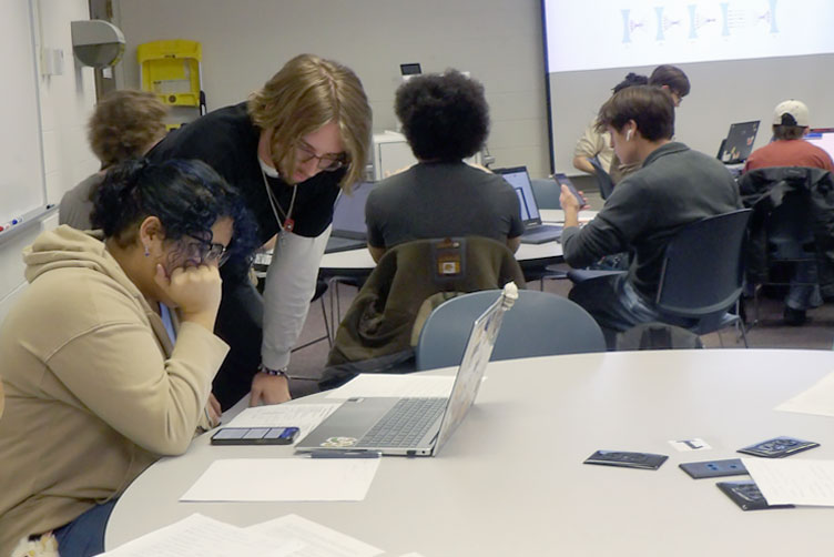 Group of students working, a LA is helping one student in the group