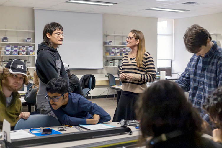 LA and Faculty are facing each having conversations and students are sitting at their group table working