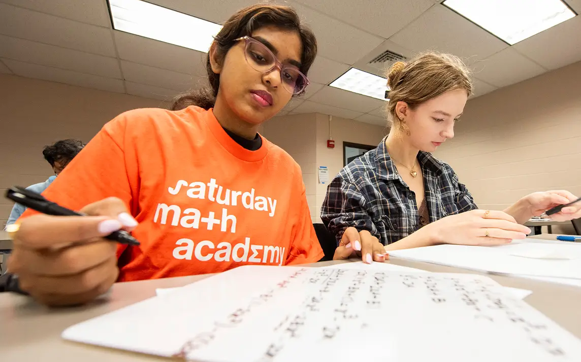 Two students sitting at a table, working on schoolwork.