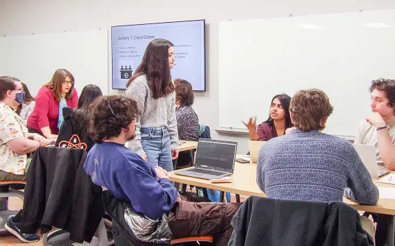A learning assistant going around and helping students in a classroom setting.