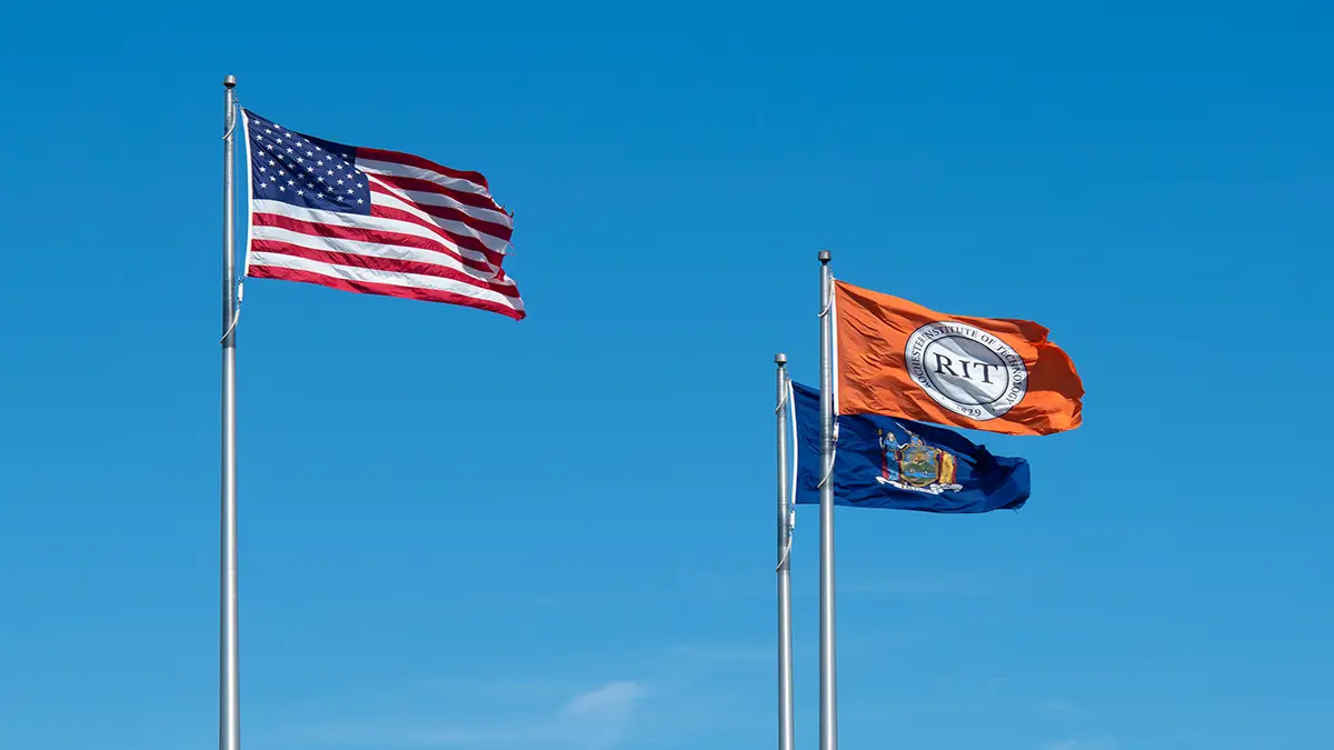 The United States, New York State, and R I T flag flying on campus.