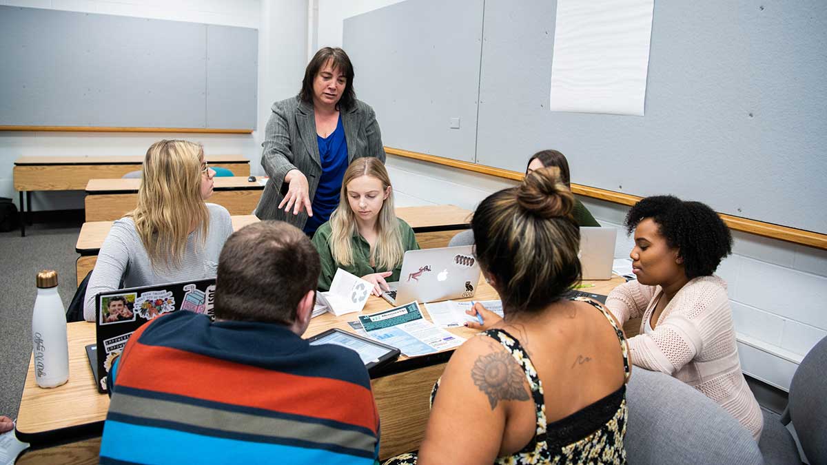 professors and students engaged in discussion in a classroom.