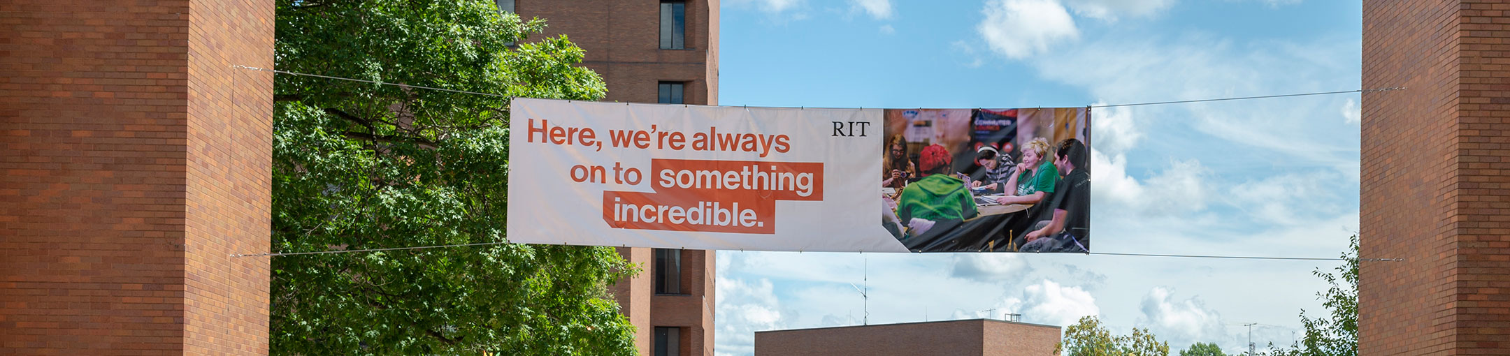 a hanging banner with a picture of a group of students and the RIT logo that says: Here we're always on to something incredible.
