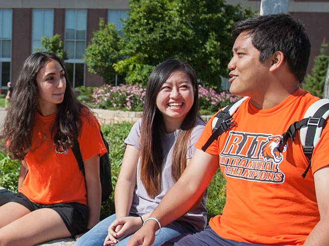 Students walking through campus on a sunny day under the shade of trees