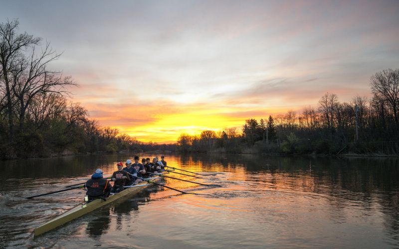 The sun rises as the RIT Rowing team practices on an April morning along the Genesee River near the Gosnell Boathouse.