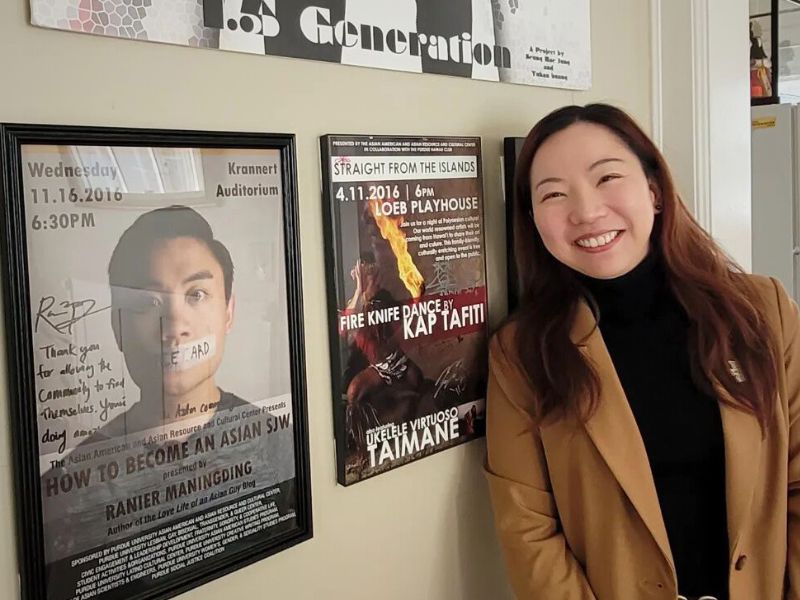 A photo of Huhan in her home with a wall on interesting posters