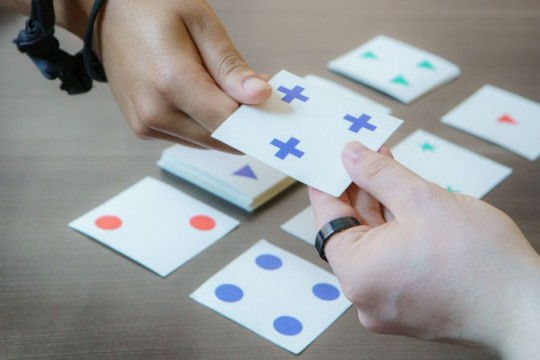 a photo of two people working on a perception activity using cards with symbols