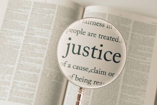 magnifying glass over a dictionary on the word justice