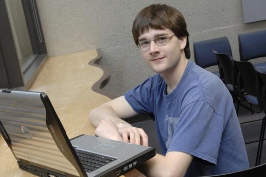 Student posing by laptop