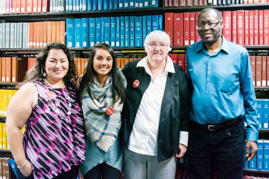 Four people together for a picture in the Wallace Library.
