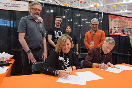 People signing documents at conference