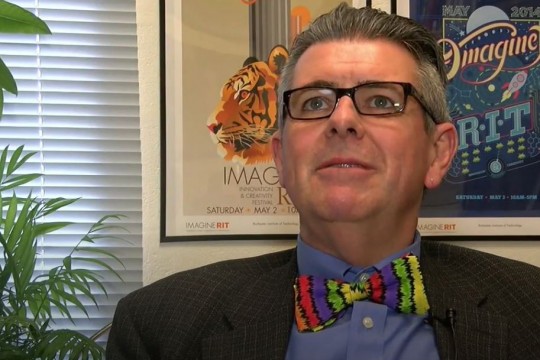 Professor with glasses and colorful bowtie sits in office