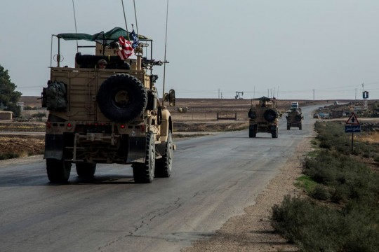 U.S. military trucks drive down road.