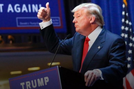 President Trump gives a thumbs-up at a podium.