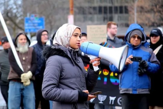 student standing in front of a crowd holding a megaphone.