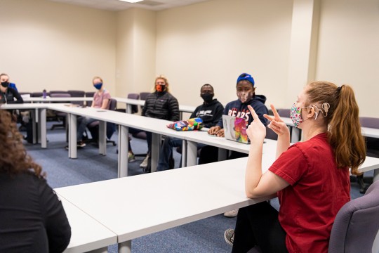 students wearing face masks and sitting socially distanced in a classroom setting.