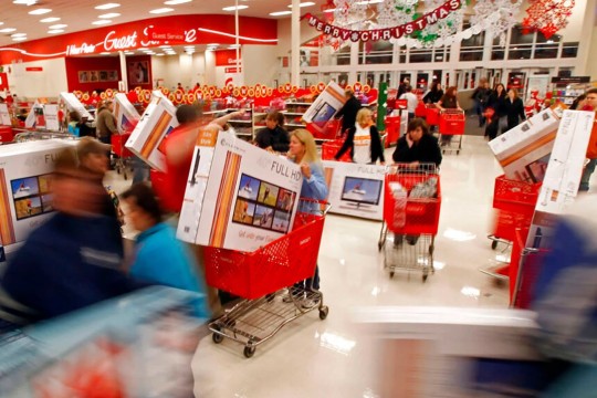 crowd of shoppers in a Target pushing carts with TVs in them.